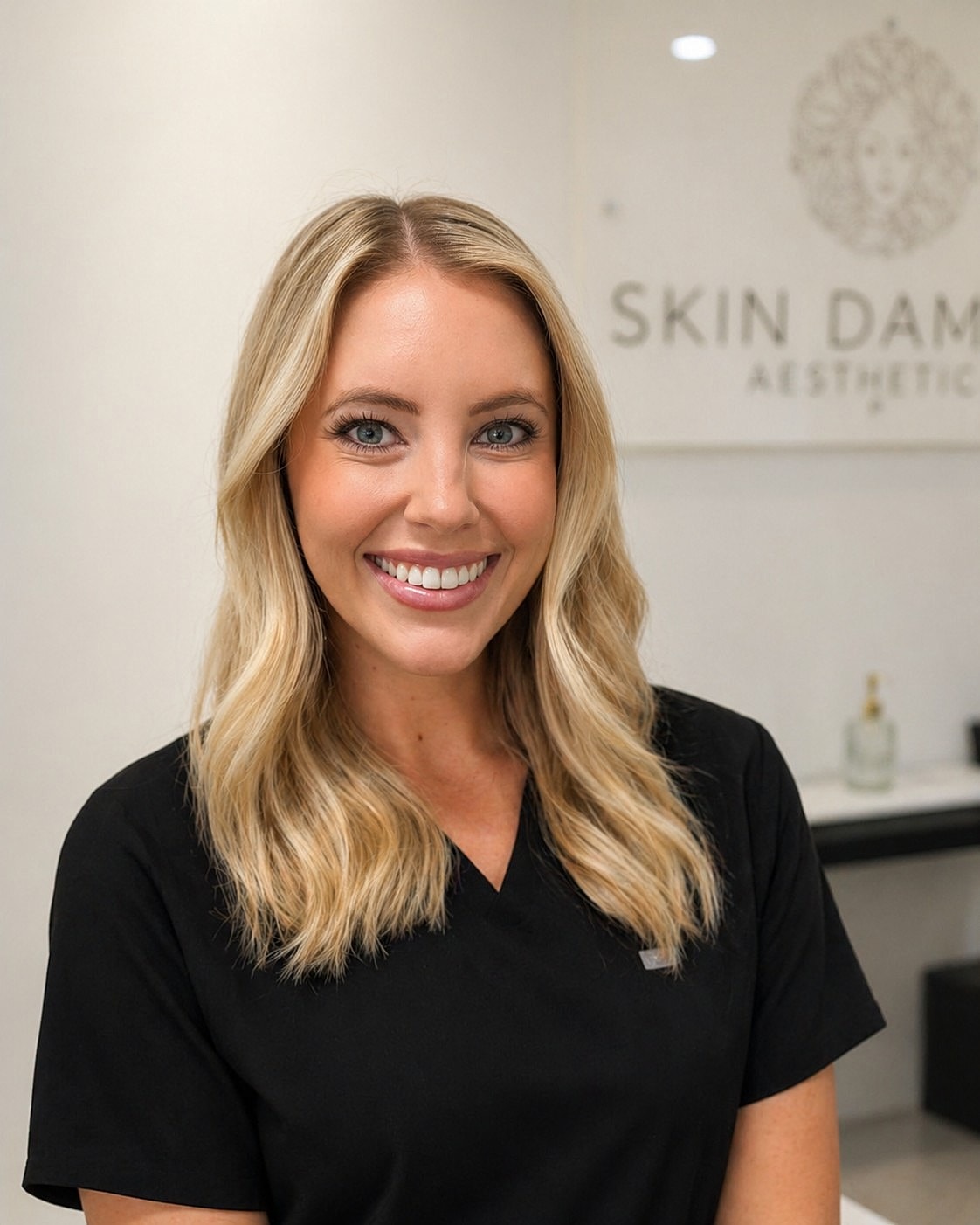 Smiling woman in black scrubs at clinic.
