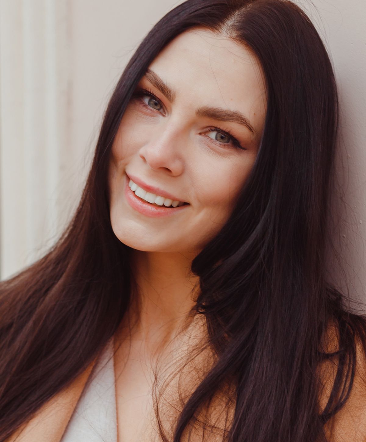 Smiling woman with long black hair outdoors.