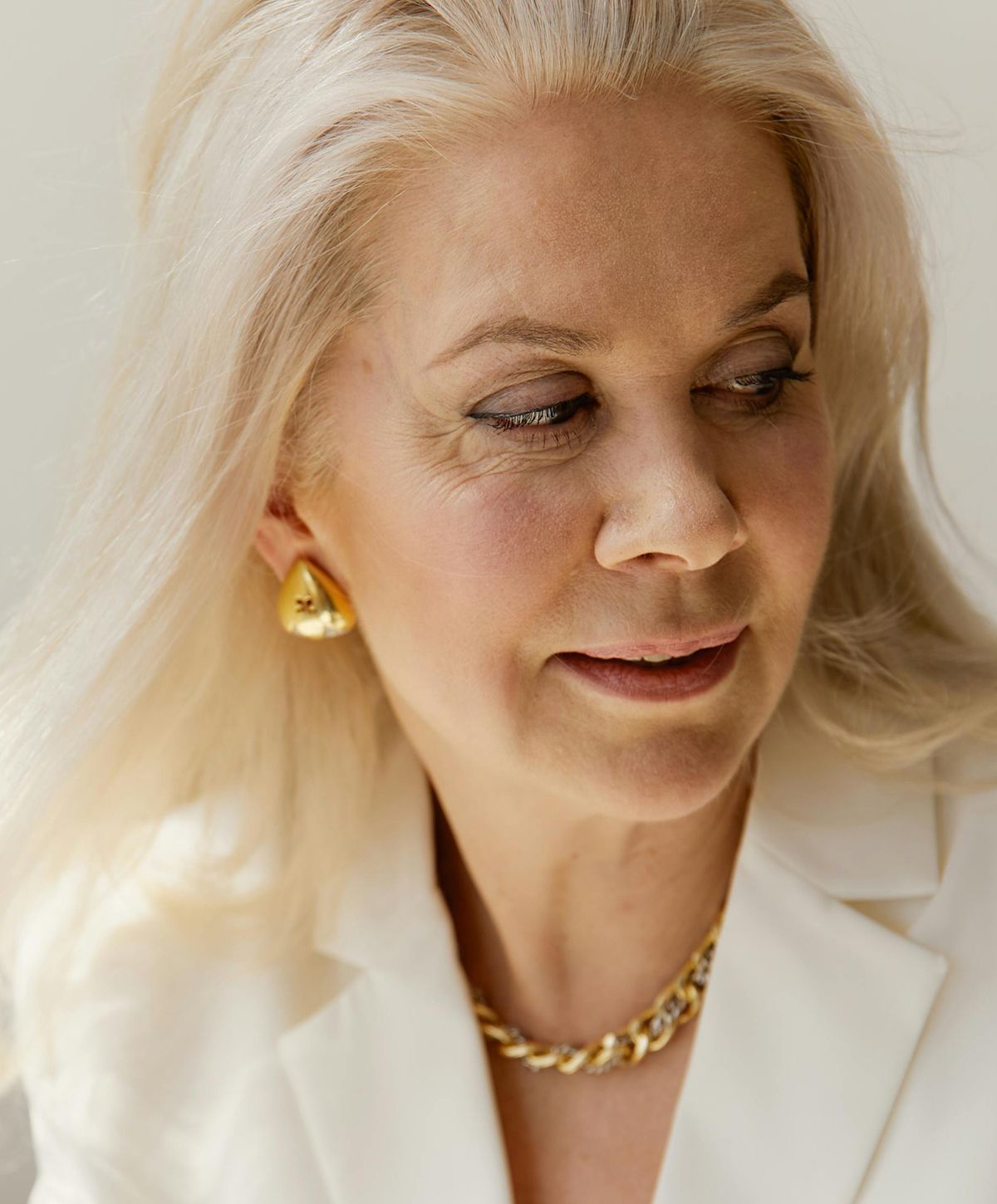 Woman with blonde hair and statement jewelry.