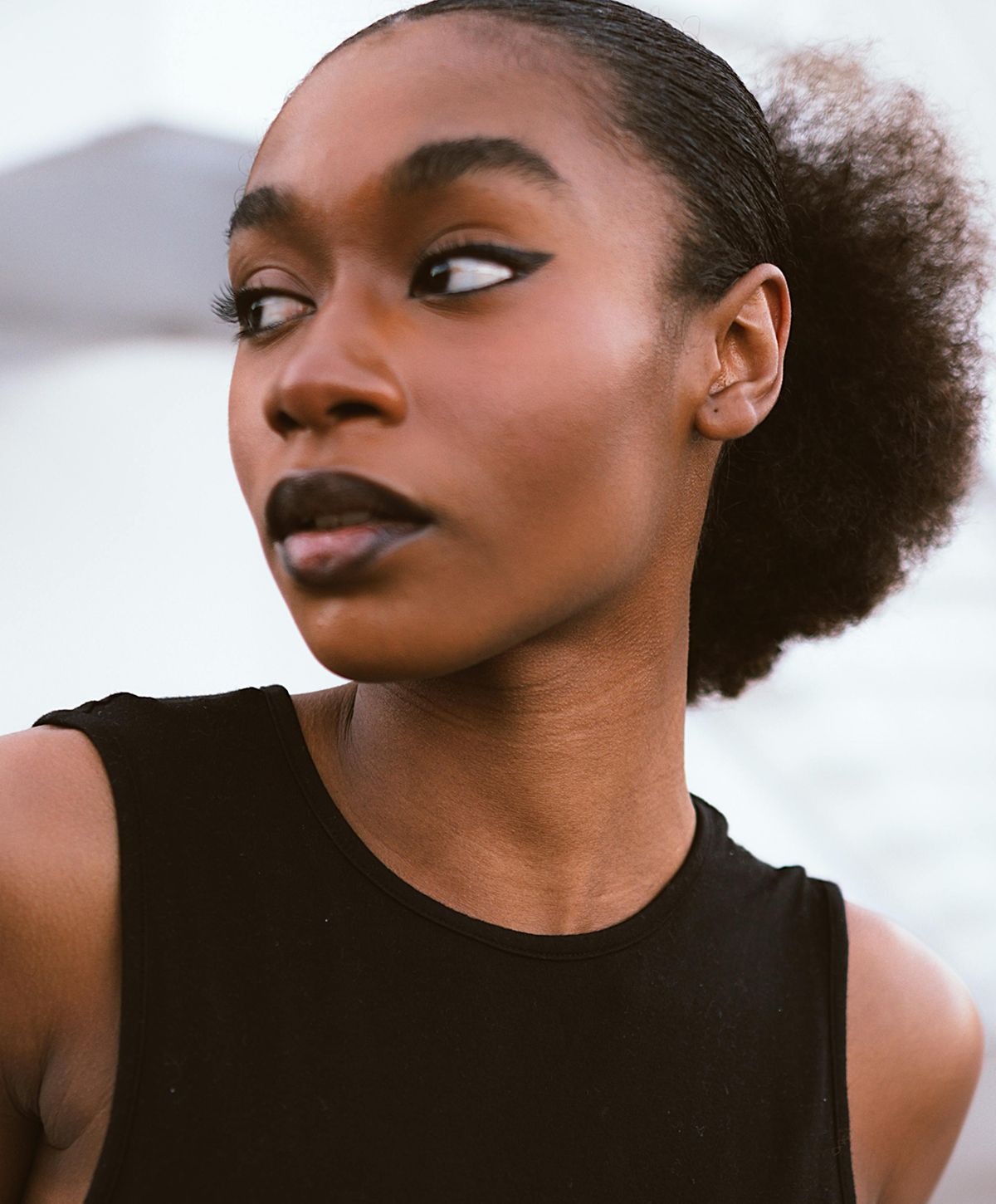 Woman with striking makeup and textured hairstyle.