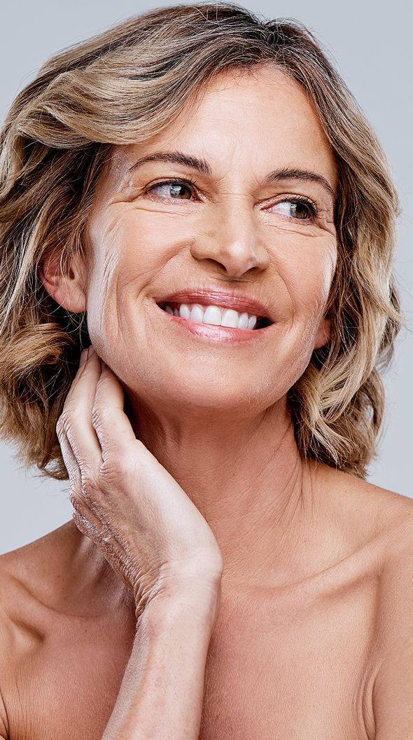 Smiling woman touching her neck and shoulder.