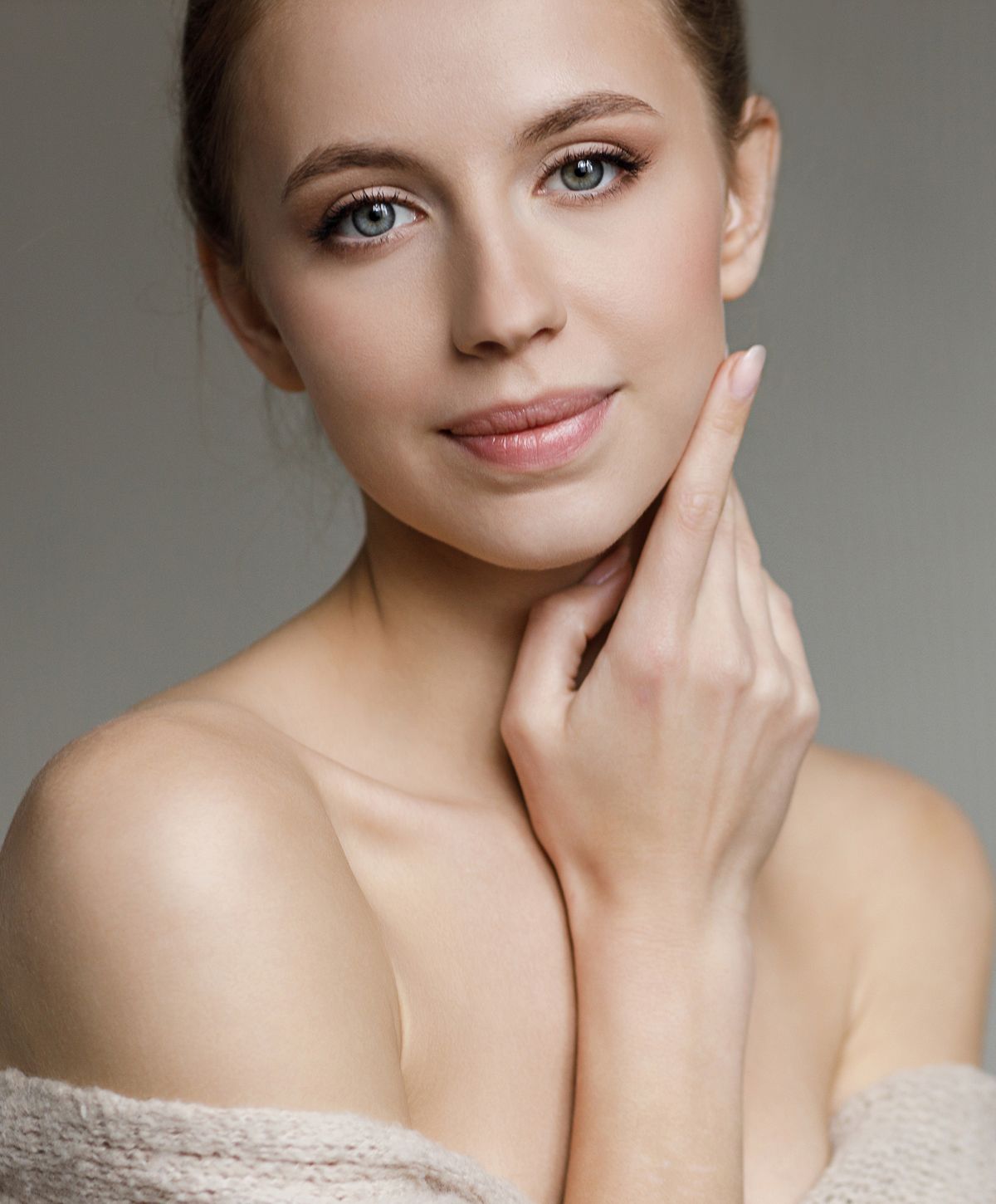 Woman with natural makeup, touching her face.
