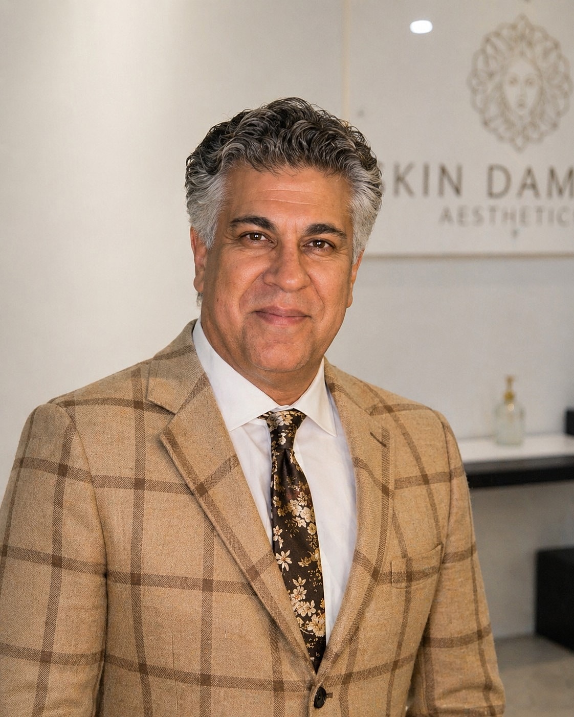 Man in a formal outfit smiling indoors.