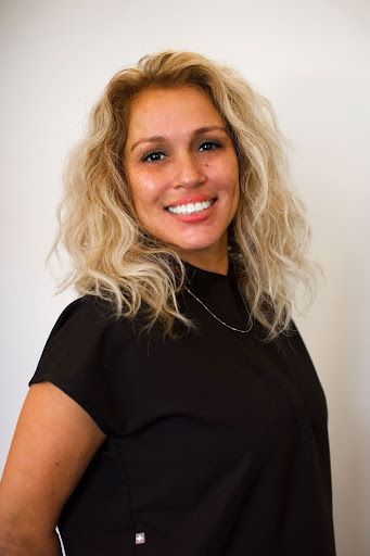 Woman with curly hair smiling in black top.
