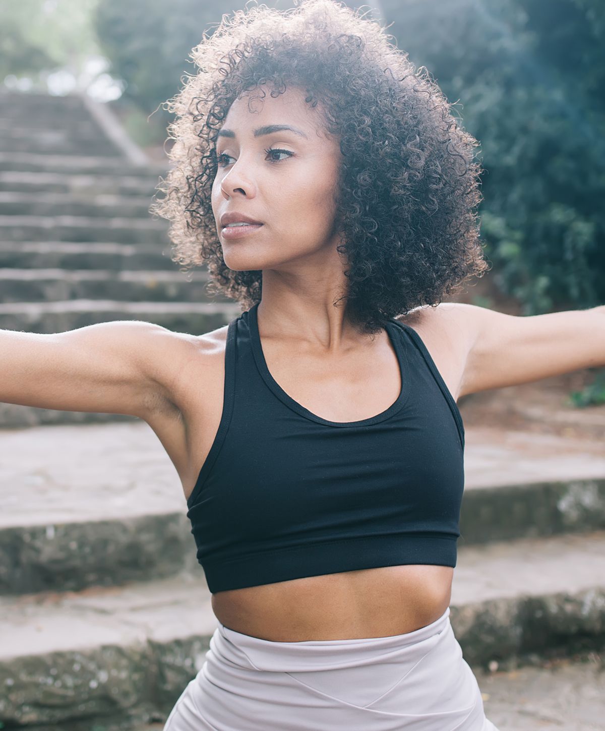 Woman exercising outdoors with curly hair.