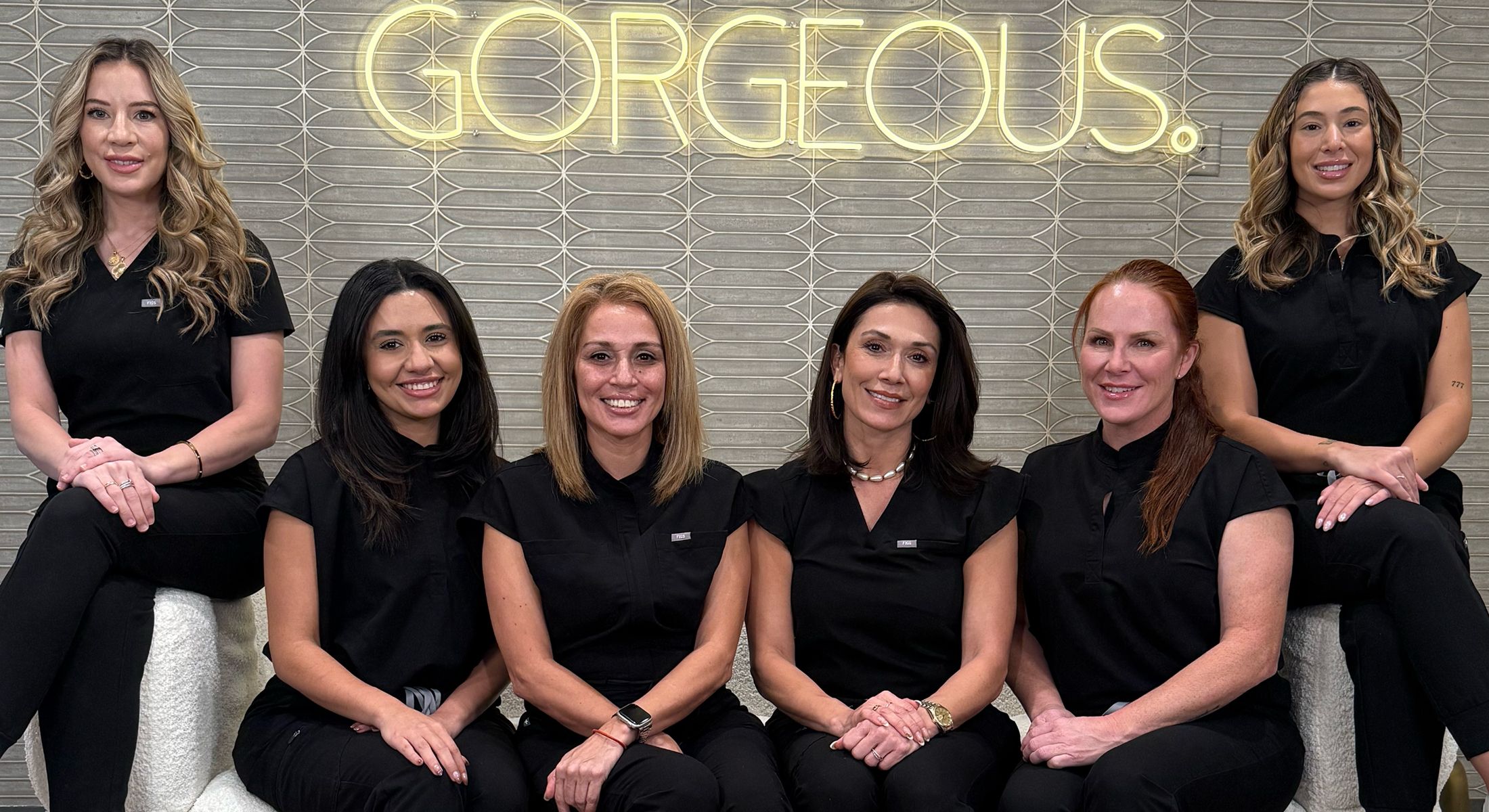 Group of professionals posing in front of sign.