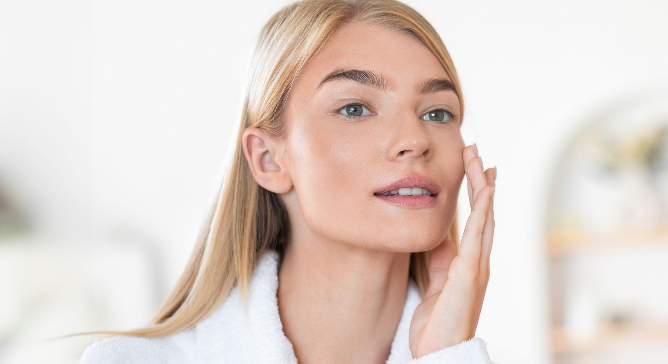 Woman applying skincare in bright, minimalistic setting