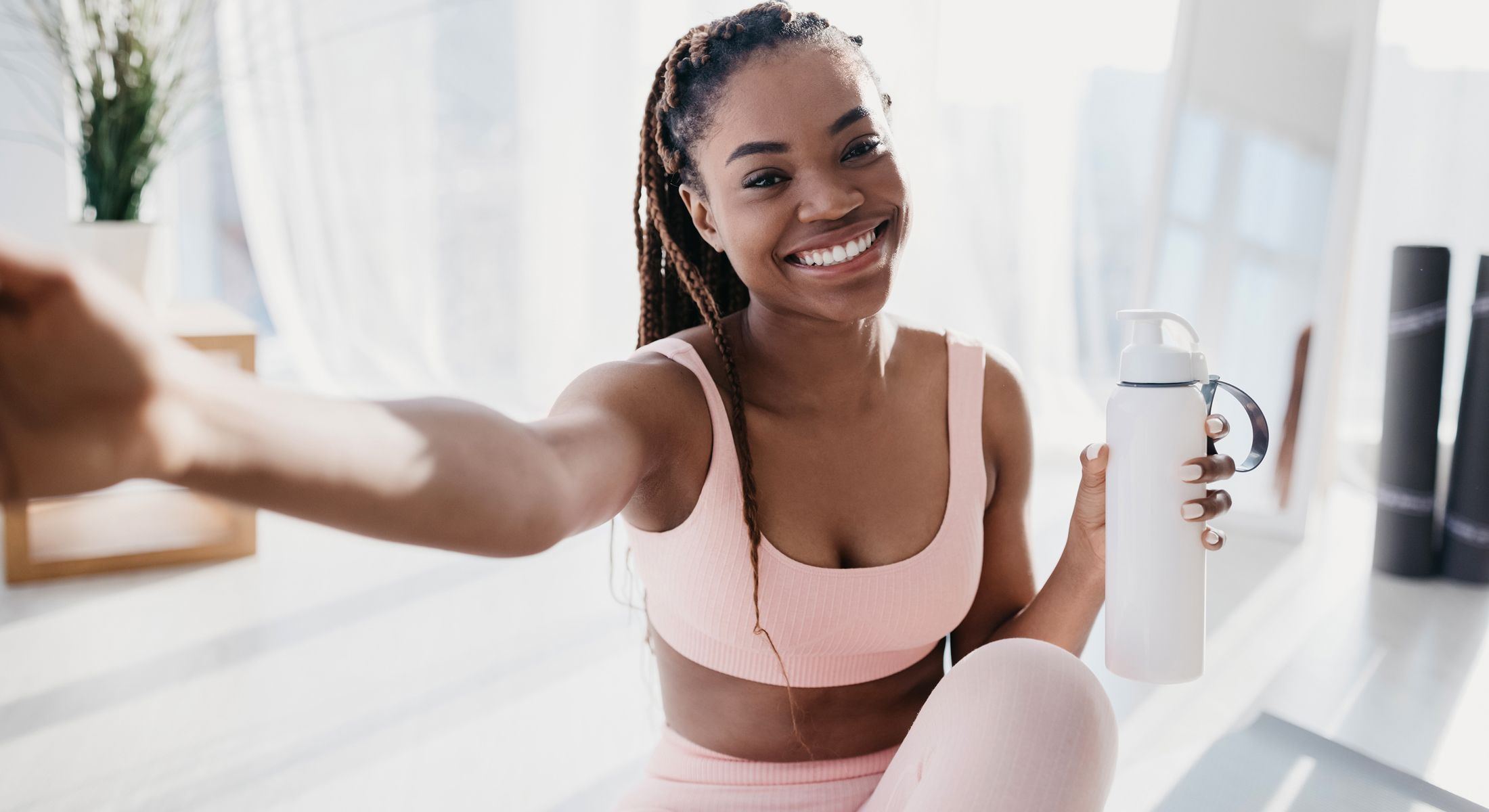 Smiling woman with water bottle in fitness setting.