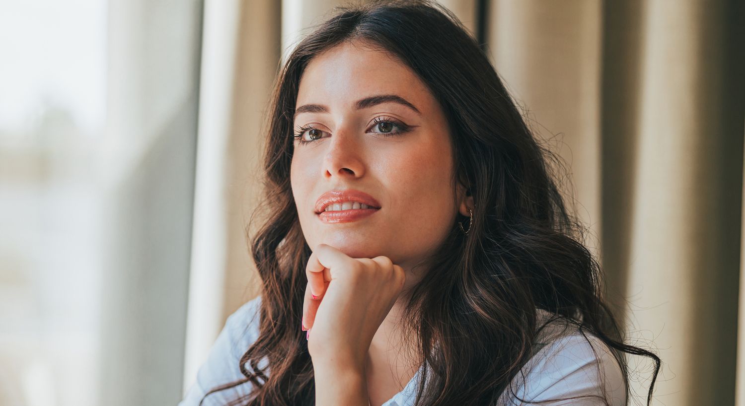 Smiling woman leaning against wall in office.